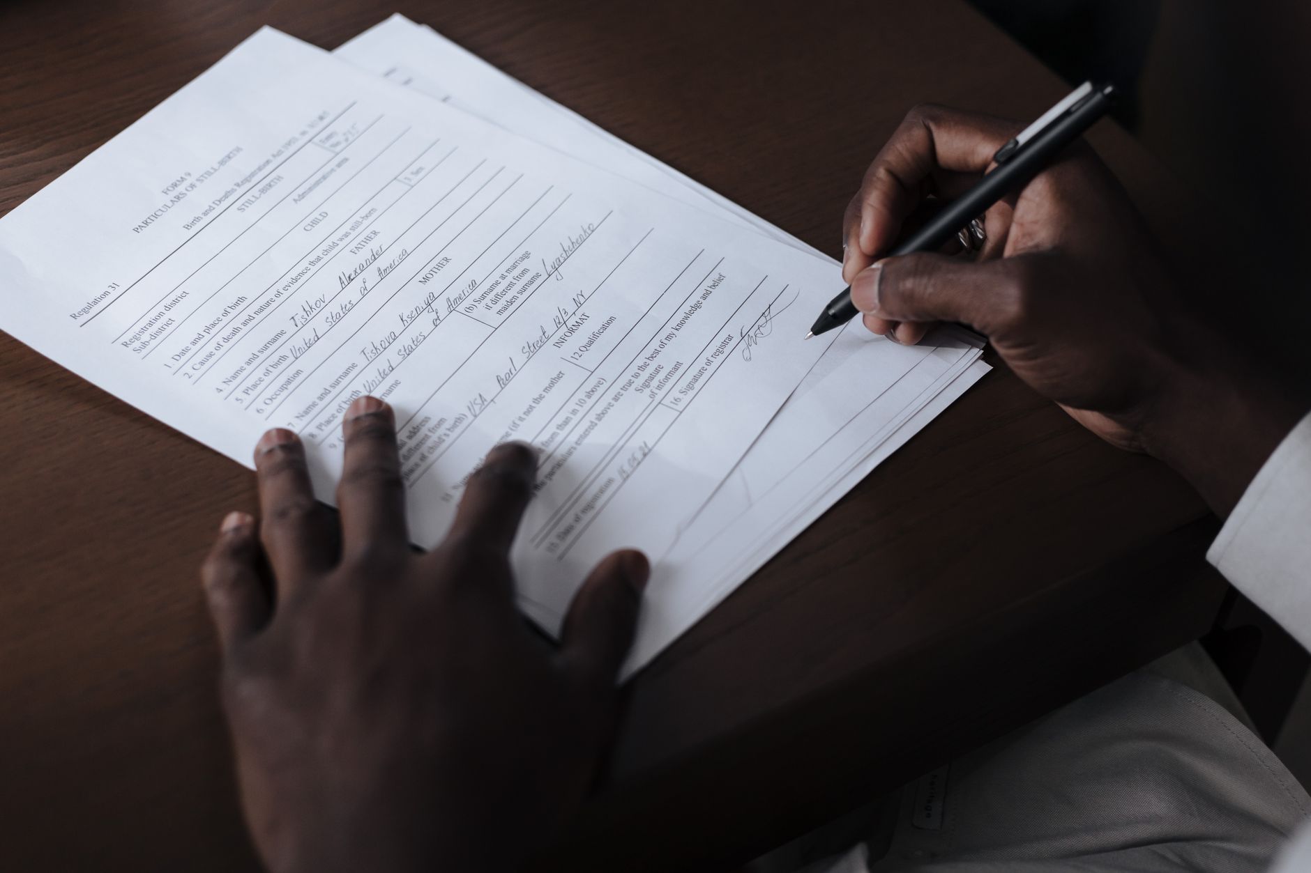 Man signing a document at a table with a pen